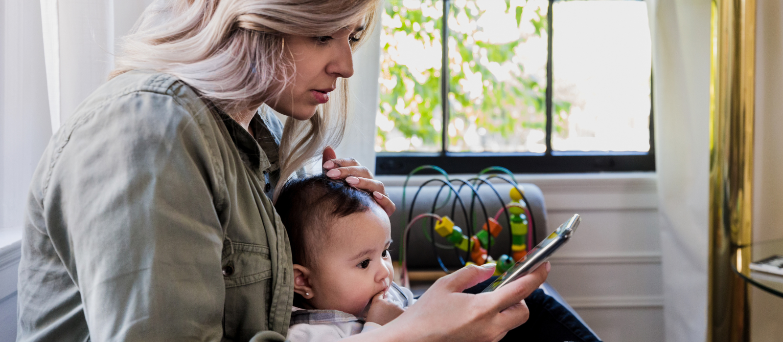 Mother holding baby looking at phone