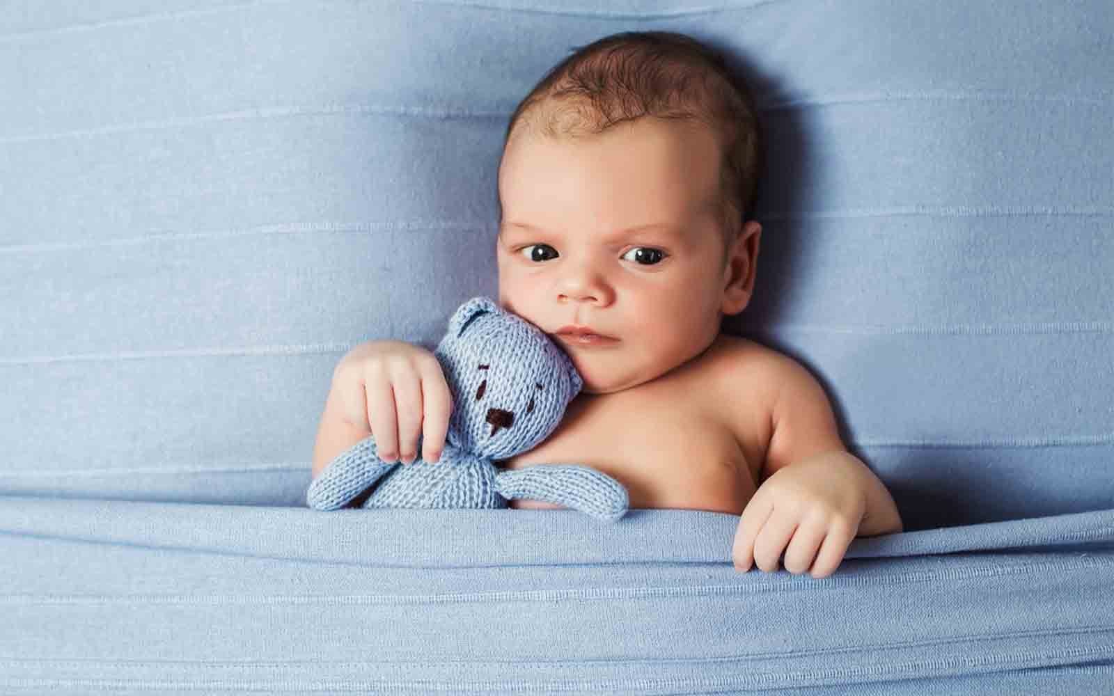 Picture of a baby holding a teddybear who is going through a sleep regression